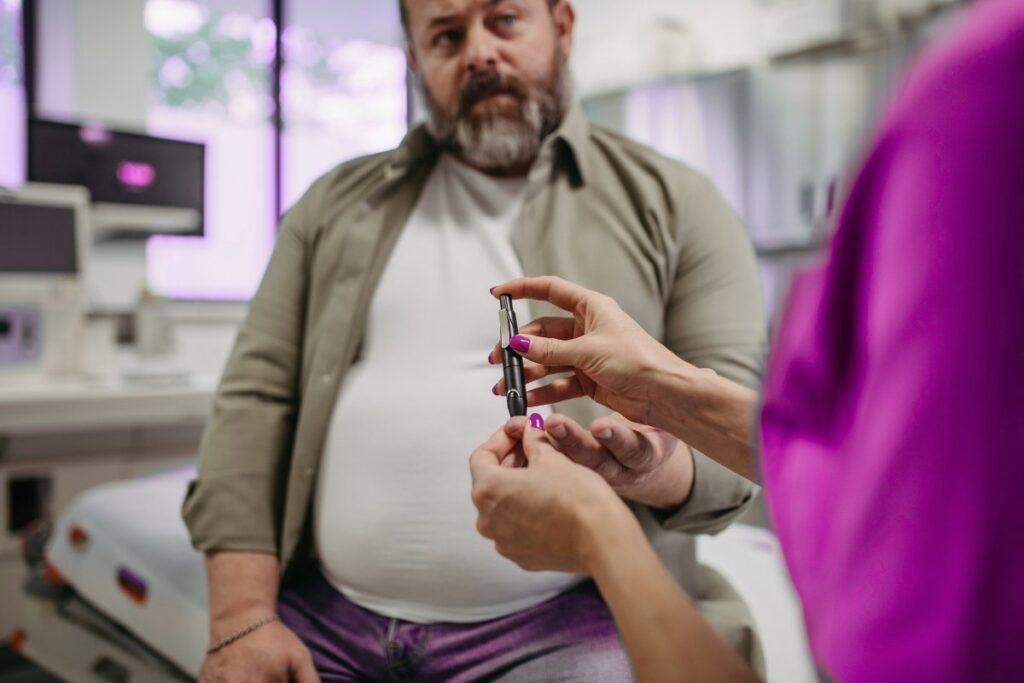Healthcare professional checking blood sugar levels with a glucometer on a patient’s finger during a diabetes consultation.