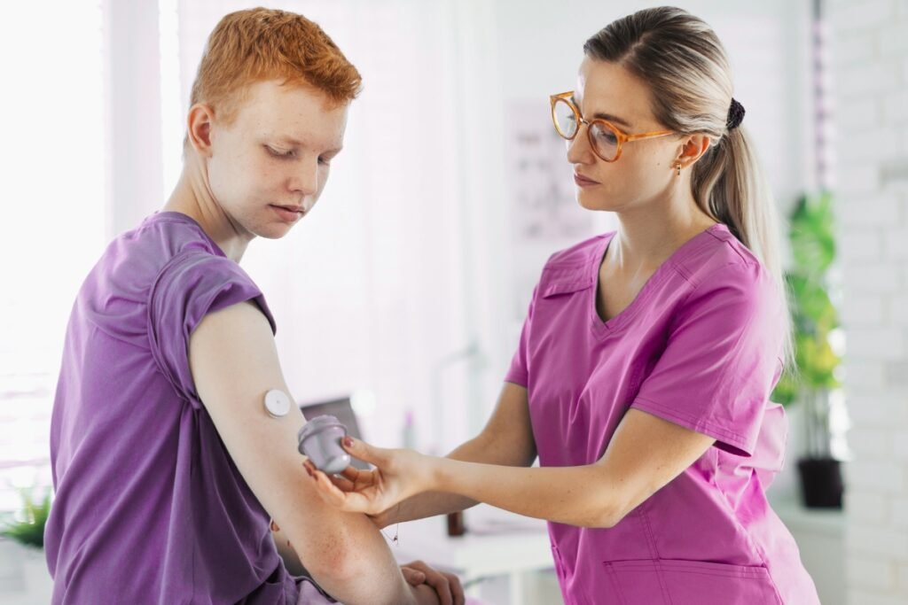 Nurse scanning a glucose monitor sensor on a teenage patient’s arm during a diabetes checkup.