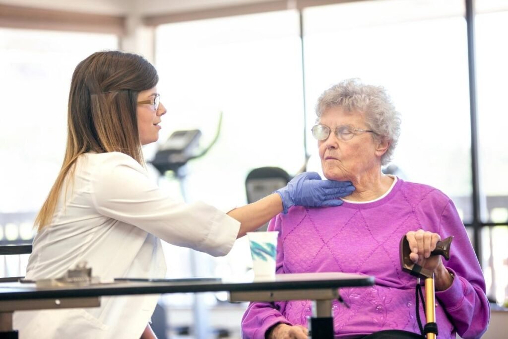 A healthcare professional checks the throat of an elderly patient during a therapy session.